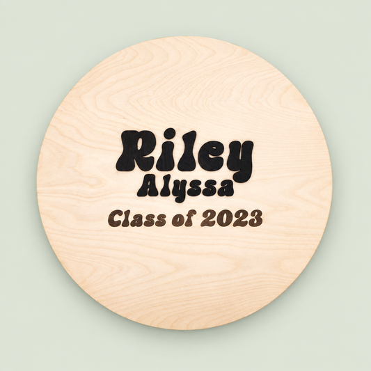 Round wooden graduation guest book personalized Riley Alyssa, Class of 2023, on a soft sage background.