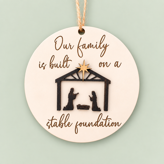 Round layered nativity ornament reading Our family is built on a stable foundation.