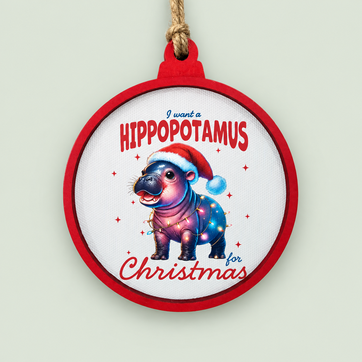 Red-framed Christmas ornament featuring a baby hippo wearing a Santa hat and holiday lights.