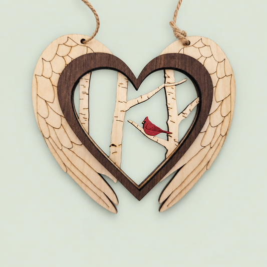 Layered wooden angel-wing heart ornament with birch trees and a red cardinal.