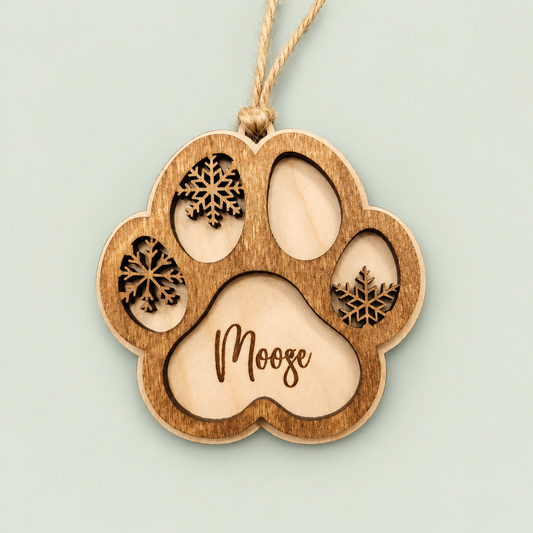 Layered wooden paw ornament personalized with Moose, snowflake details and a twine hanger on soft sage.